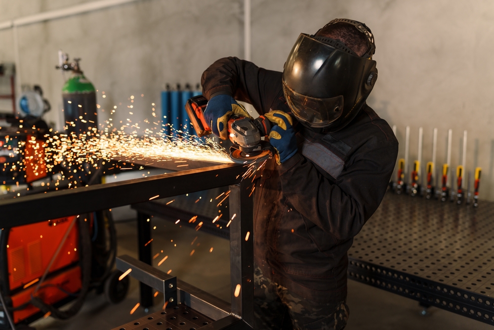 Metalworker,Wearing,Protective,Gear,Uses,An,Angle,Grinder,,Creating,A