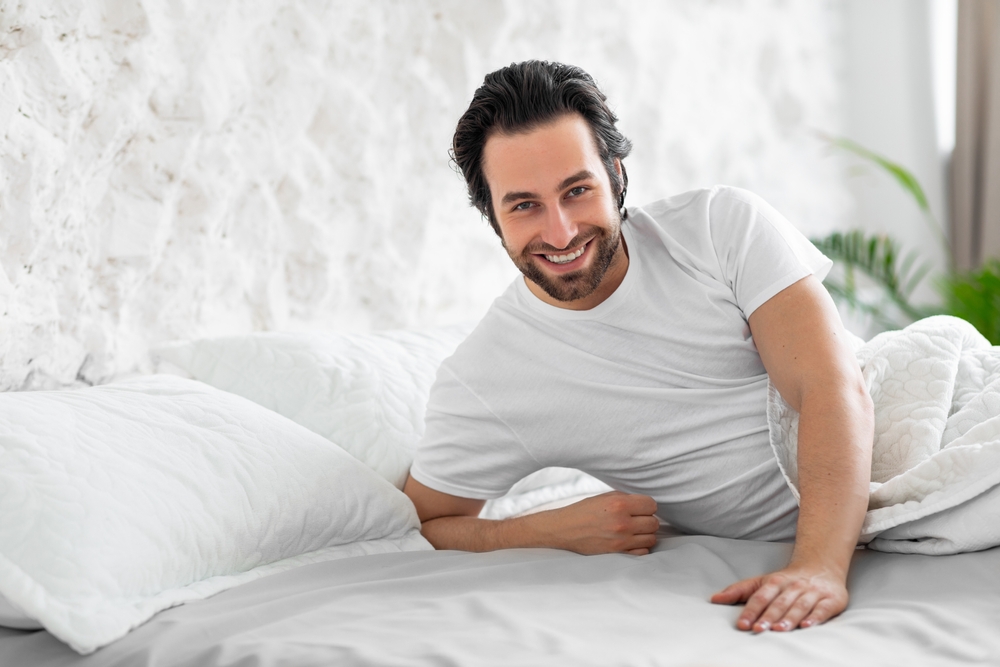 Handsome,Young,Man,In,Pajamas,Laying,In,Bed,,Touching,Empty