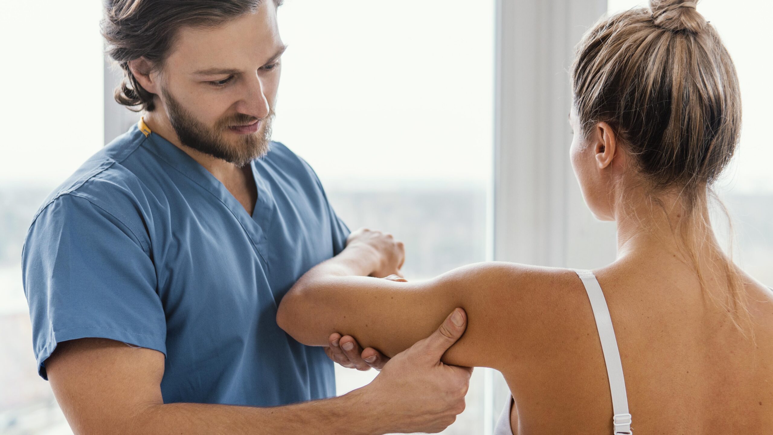 front-view-osteopathic-therapist-checking-female-patient-s-shoulder-movement