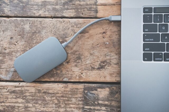 Hard disk extern conectat la un laptop pe un birou, folosit pentru copia de siguranță a fișierelor