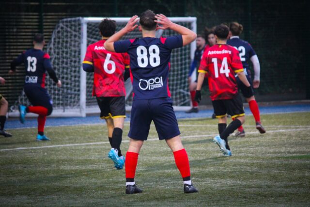 Meci de minifotbal între echipe amatoare pe un teren sintetic, cu jucători în veste de culori diferite