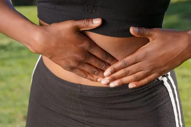 Persoană cu mâinile pe abdomen, simptome digestive
